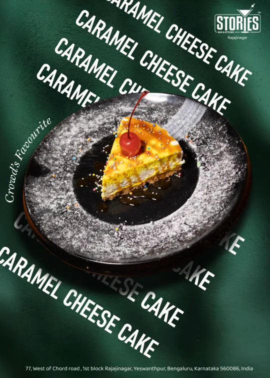 Slice of caramel cheesecake topped with a cherry on a dusted black plate against a green background – dessert poster for Stories Bar & Kitchen, Rajajinagar