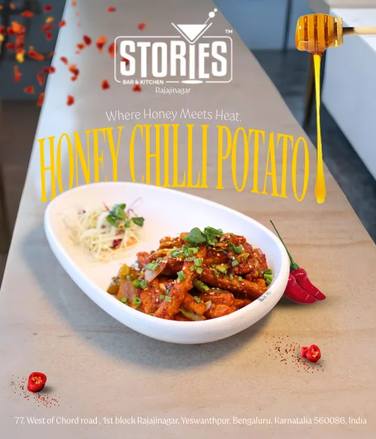 Honey chilli potato in a white bowl with honey dripping from a dipper and red chillies – food poster for Stories Bar & Kitchen, Rajajinagar