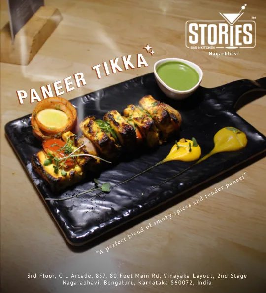 Grilled paneer tikka skewers with mint chutney on a black slate board – food poster for Stories Bar & Kitchen, Nagarbhavi